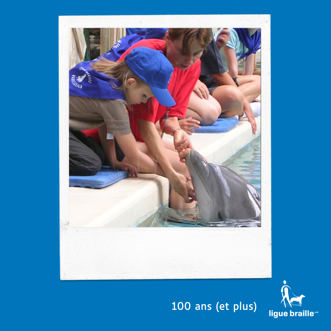 Photo d’un enfant aveugle caressant un dauphin au Boudewijn SeaPark, lors du BrailleDay, de 2003.  